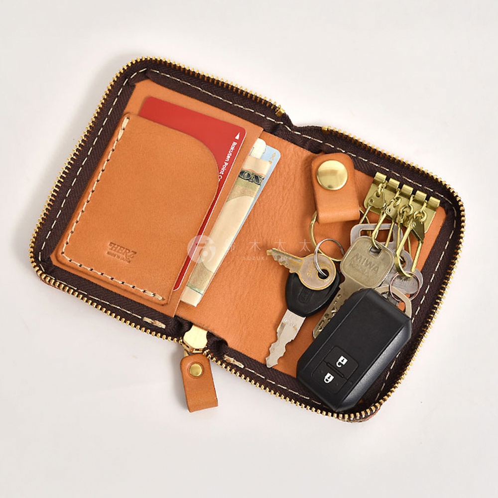 職人手作皮革多用途收納鑰匙包，皮革顏色為棕褐色，內有卡槽可放信用卡和鈔票，並附有四個金色鑰匙鉤，可掛置多把鑰匙，包括汽車遙控器。