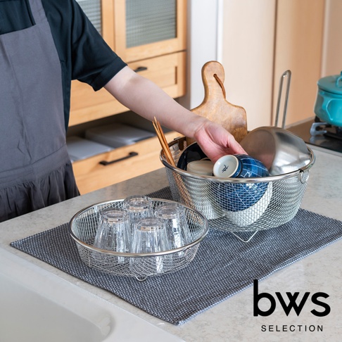 不鏽鋼圓形淺型瀝水籃，內有數個玻璃水杯。另一個較大的同款瀝水籃內有藍白花紋碗、鍋子及筷子。