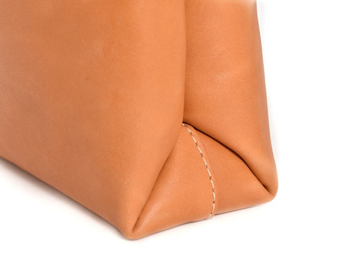 職人手作皮革直式軟皮托特包 (T-205) L，展示包包底部與側面皮革接縫處，呈現溫暖的棕褐色柔軟皮革材質，以及精緻的米白色縫線細節。