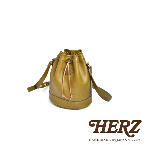 職人手作皮革束口單肩包，橄欖綠色，採用柔軟皮革製成，束口設計配有粉色抽繩，可斜揹或單肩揹。