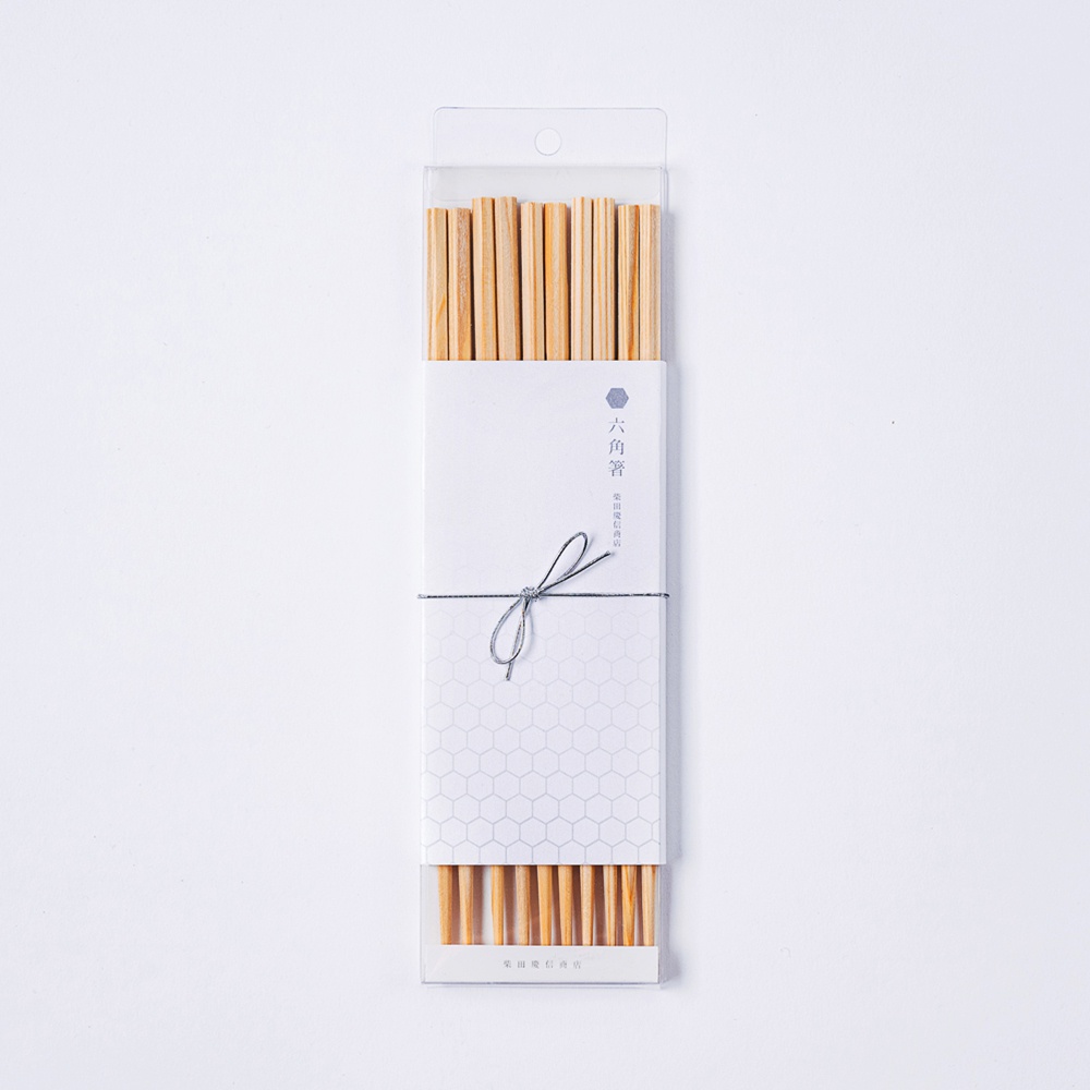 銀色包裝盒內的五雙二十三公分長的木質六角形筷子，筷子為天然木色，頂部有細繩綁著。
