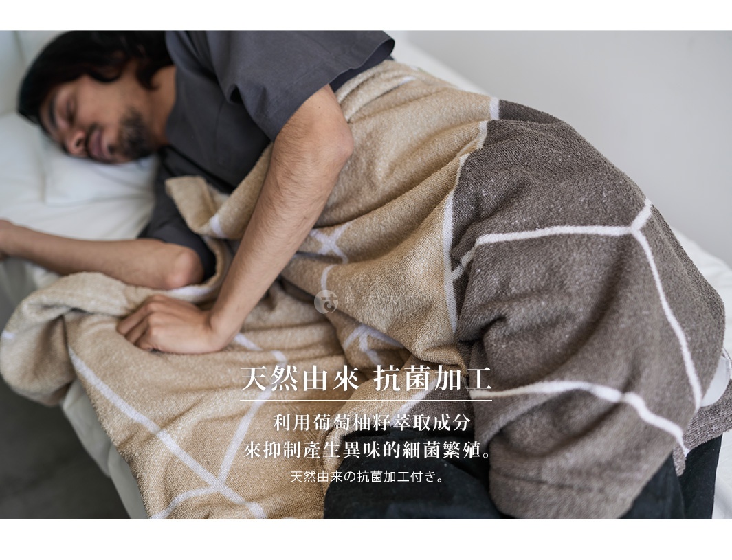 男人蓋著一條有幾何圖案的抗菌純棉毛巾，毛巾呈現米色和深棕色。
