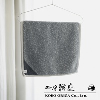 灰色棉麻混紡雙色快乾浴墊，邊緣帶有淺灰色滾邊，懸掛在衣架上。