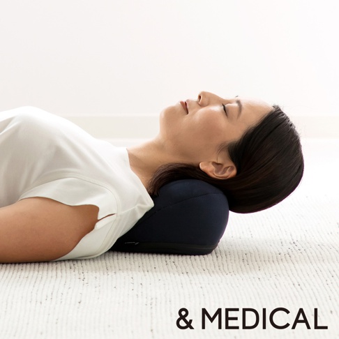 一位女性仰躺，頭部枕在深藍色肩頸按摩紓壓枕上，枕頭採用網狀布料材質，提供肩頸支撐。