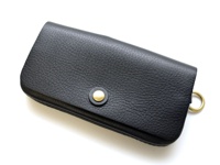 黑色荔枝紋皮革製成的長夾，配有金色按扣及環狀吊飾，設計簡約。