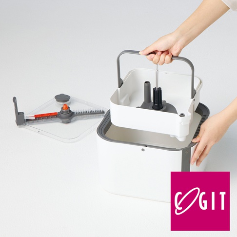 一雙手正在組裝一款白色與灰色的 COGIT 旋轉拖把清潔桶，清潔桶內部結構露出，一旁放置著帶有刷頭的透明蓋子，整體設計簡約實用。
