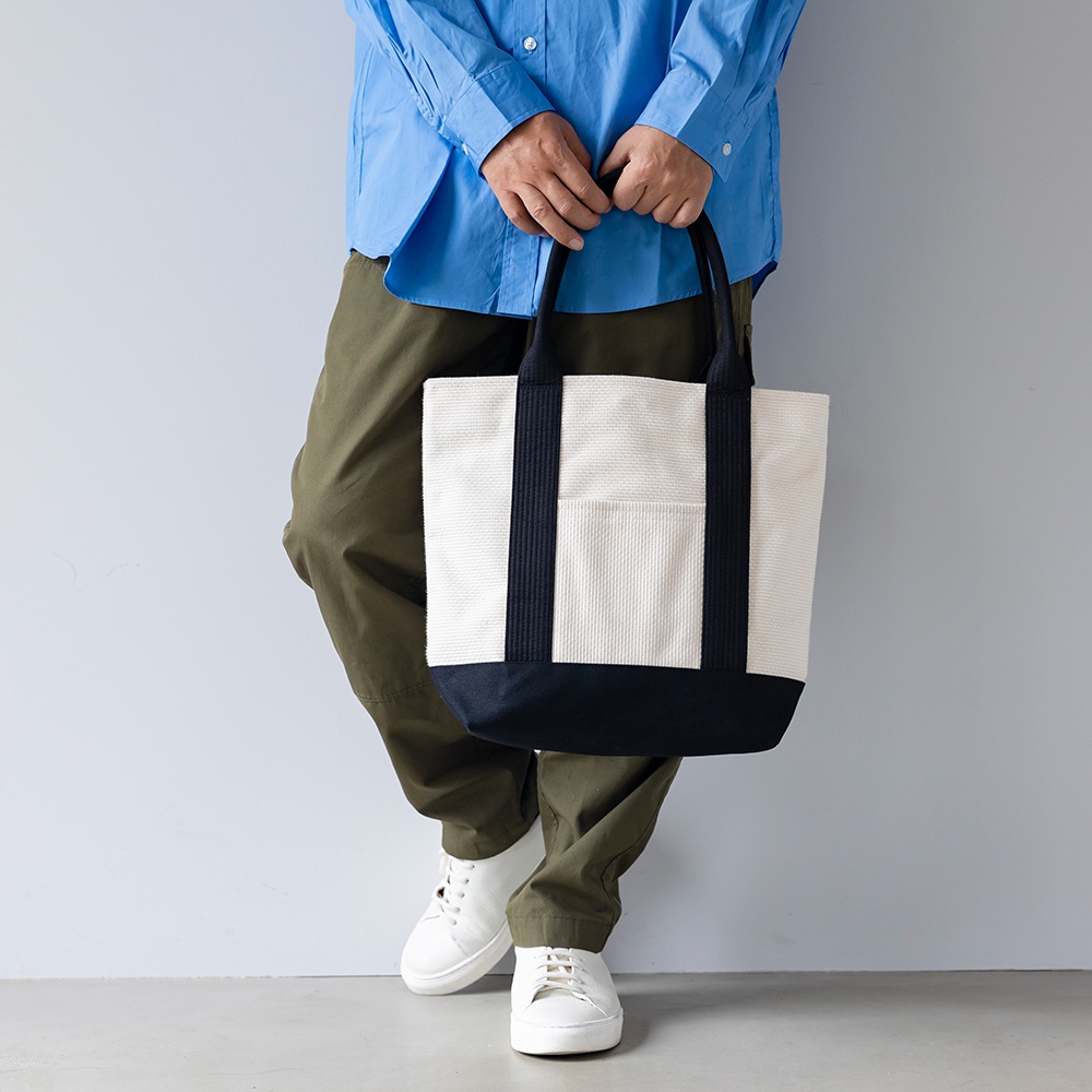 三河木綿刺子織OBI托特包，米白色織紋主體搭配海軍藍底部與提把，側面有海軍藍條紋與一個米白色外袋。