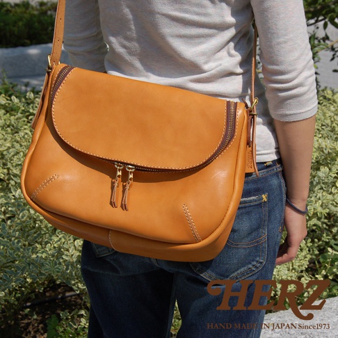 日本HERZ職人手作皮革大容量馬鞍包，駝色Stare皮革，設有雙拉鍊主袋，斜肩背款式，背面刻有HERZ標誌及since 1973字樣。