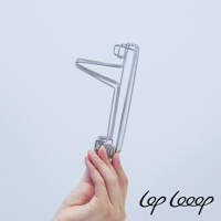 手持一個閃亮的銀色伸縮式不鏽鋼水壺瀝水架，其由彎曲的金屬絲製成，設計簡潔。