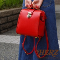 職人手作皮革迷你後背醫生包，採用鮮紅色牛皮製成，包身方正，帶有經典的醫生包鎖扣和金屬細節，附有可調整的皮革背帶。