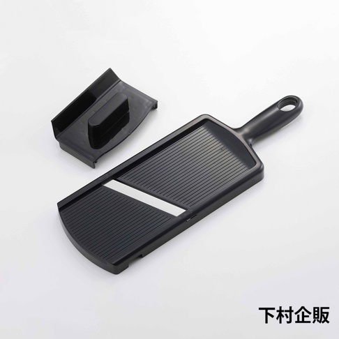 黑色超薄切高麗菜刨絲器，附有一個黑色的推料器。刨絲器為長方形，帶有手柄，表面有細密的刨絲紋路和一個銀色刀片。