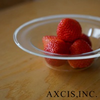 一個透明玻璃製成的深型點心碗，裡面盛有幾顆鮮紅色的草莓，碗放在木質桌面上。