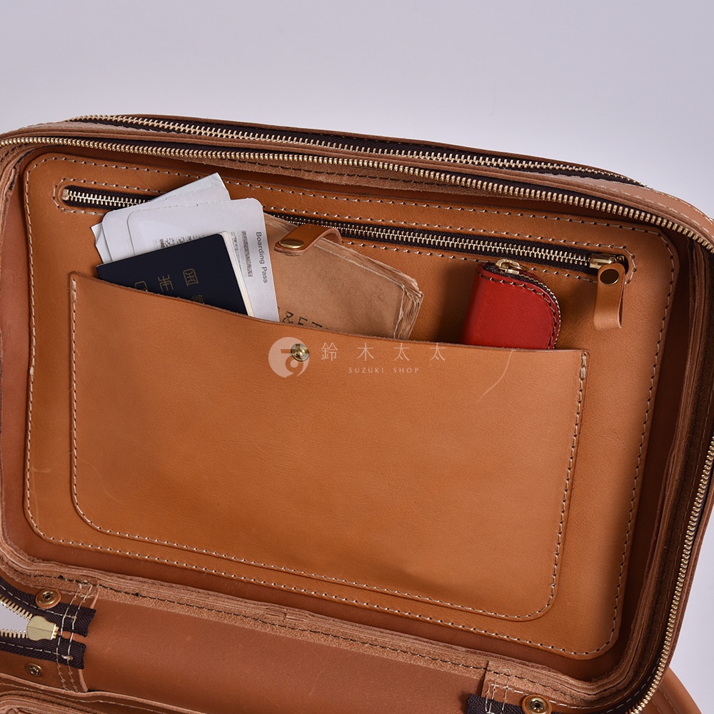 職人手作皮革兩用商務後背包 R-33，展示內裡隔層，包含一個大型皮革插袋，可放置護照、機票等物品，另有拉鍊暗袋及一個紅色皮革零錢包。