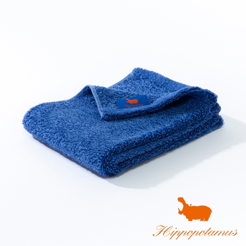 藍色竹棉混紡長毛巾，質地厚實柔軟，帶有品牌橘色河馬標籤。