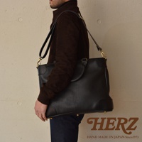 職人手作皮革Organ兩用商務托特包，黑色皮革材質，設有頂部提把及可拆卸肩帶，包身有金屬腳釘裝飾。