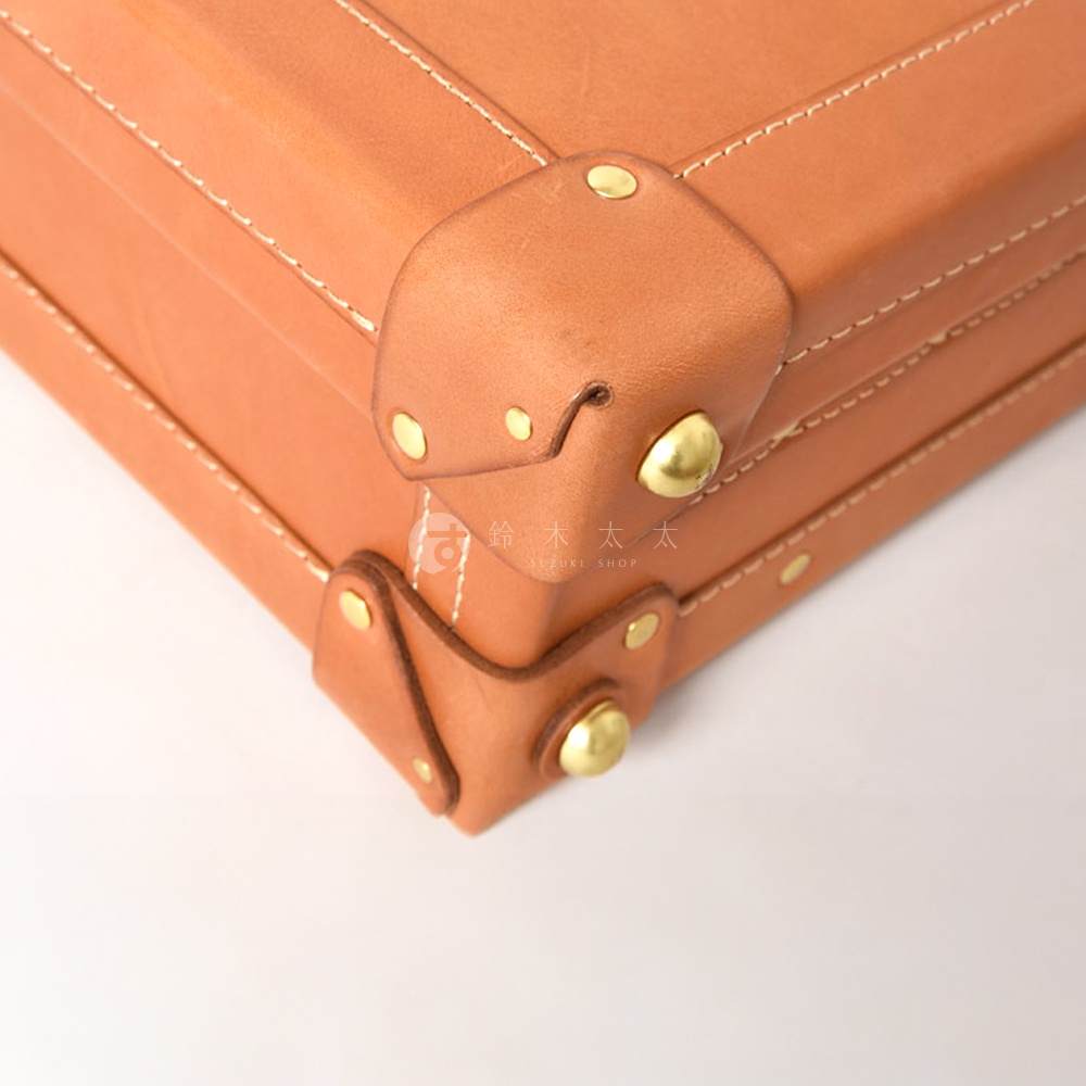 職人手作皮革英倫風便攜手提行李箱 TR-1，近拍展示箱角細節，採用棕褐色皮革，搭配金色鉚釘與白色縫線，展現經典工藝。
