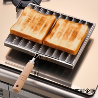 瓦斯爐專用炭烤風萬用燒烤盤，由不鏽鋼製成，配有木柄，盤內有兩片烤至金黃色的吐司。