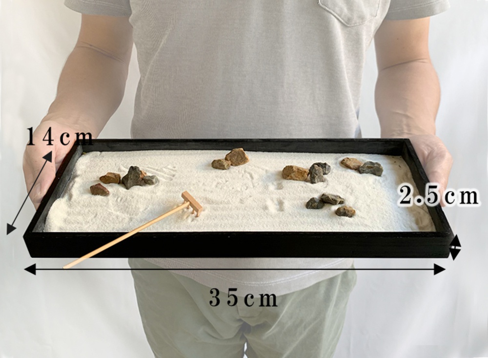 黑色長方形木質托盤，內含白色細沙，散佈著大小不一的灰色及褐色岩石，另有一支木製耙子。托盤尺寸標示為長 35 公分，寬 14 公分，高 2.5 公分。