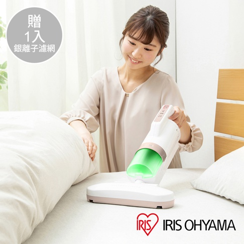 一位女性使用白色和粉色的IRIS OHYAMA氣旋偵測除蹣清淨機，正在清潔床鋪。清淨機具有透明綠色的集塵筒，機身上有操作按鈕。
