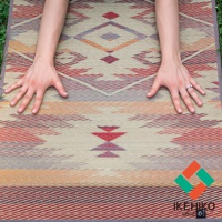 藺草編織瑜珈墊，以大地色系為底，搭配紅色、橘色、紫色和藍色的幾何菱形圖案，材質為藺草，質感樸實。