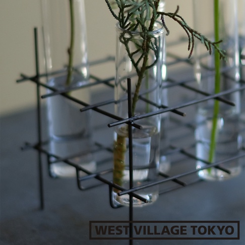 黑色金屬網架，固定著六個透明玻璃試管花器，每個試管中都插有綠色植物和水。