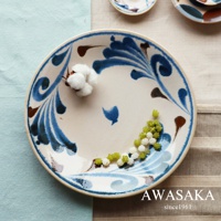 一個白釉陶瓷料理盤，盤面繪有藍色與棕色的植物紋飾，盤中置放著一團棉花和少量白色、綠色糖珠。