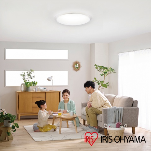 一家三口在客廳的地毯上，小女孩坐在圓桌旁，和父母一同享受悠閒時光，IRIS OHYAMA 的 LOGO 在圖片右下方。
