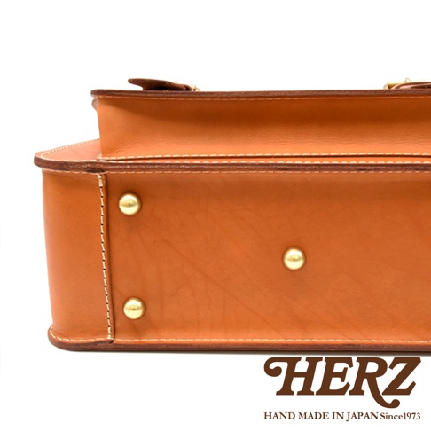 職人手作皮革經典雙扣兩用單肩包，採用光滑的棕褐色皮革製成，配有金屬釘和縫線細節。