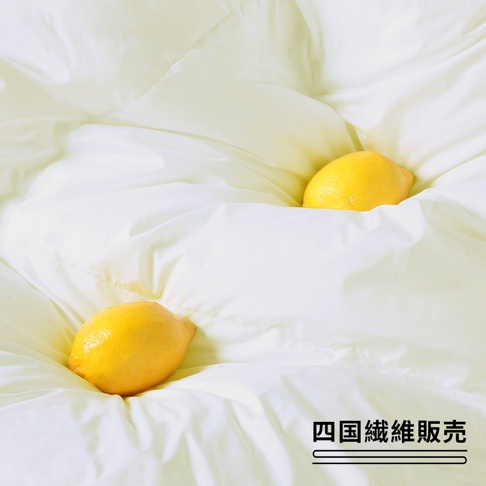 潔白蓬鬆的雲絨被，表面有細緻的縫線，兩顆黃色檸檬散落在被褥中，營造柔軟舒適的視覺效果。