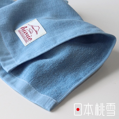 淺藍色紗布方巾，質地柔軟，一面為細緻的紗布紋理，另一面為毛圈織法，帶有紅色標籤，印有品牌名稱與「Made in Japan」。