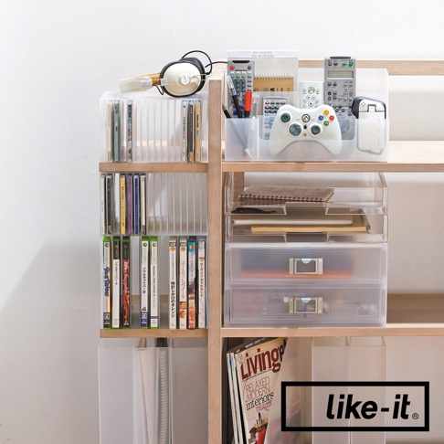 木製書架上擺放著透明可疊式收納盒，內有CD、DVD、遊戲光碟、筆、遙控器、遊戲手把、筆記本等物品。