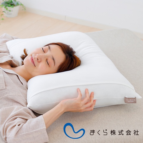 一位女子躺在純白色、柔軟蓬鬆的枕頭上，枕套應為棉質，枕頭旁有日文品牌標籤。