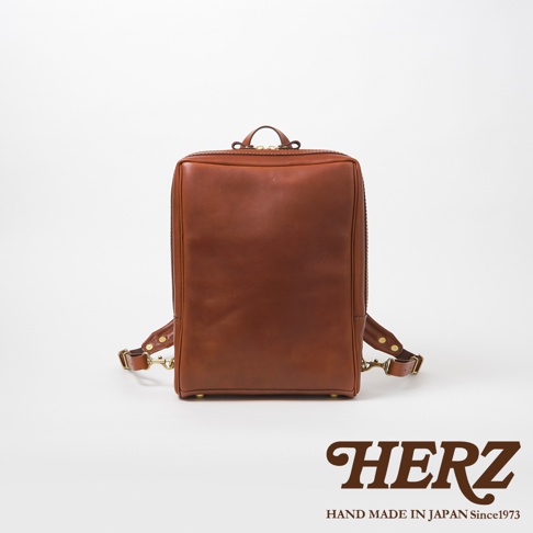 棕色皮革軟皮商務後背包，具有金屬拉鍊與扣環，展現簡約俐落的商務風格。