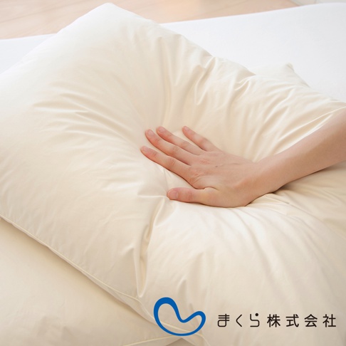 一對淺米色羽絨枕，其中一個枕頭上有一隻手。