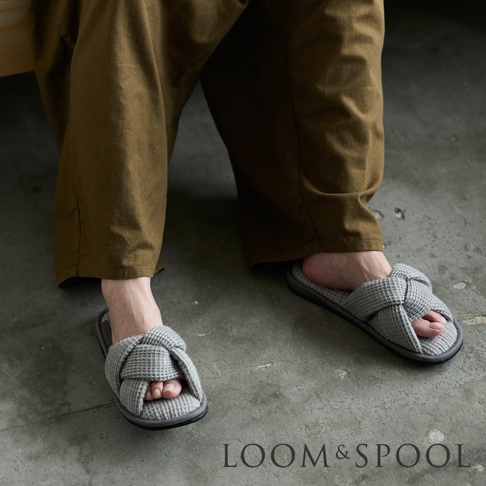 交叉編織鬆餅紋灰色室內拖鞋，鞋面為打結設計，搭配深棕色寬褲。