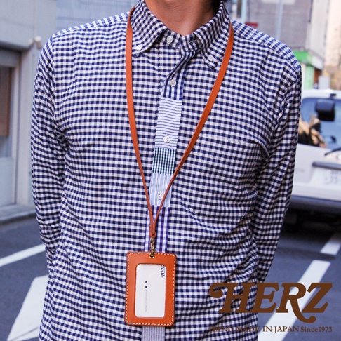 皮革直式證件識別夾，附有細長掛繩，夾身為棕色皮革，內嵌透明證件套，整體設計簡約，適合搭配日常服飾。