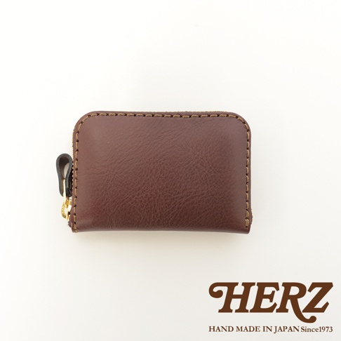 深棕色職人手作皮革拉鍊收納錢包，帶有黃銅拉鍊頭和皮革拉環，車縫線清晰可見。