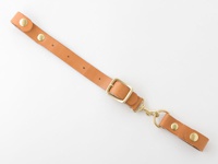 淺棕色皮革製的背包減壓胸前扣帶，配有黃銅色金屬扣環、鉤扣和铆釘。