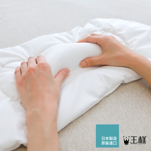 兩隻手正在觸摸一個白色的、柔軟的腰枕，腰枕被放置在一個淺色布料上。