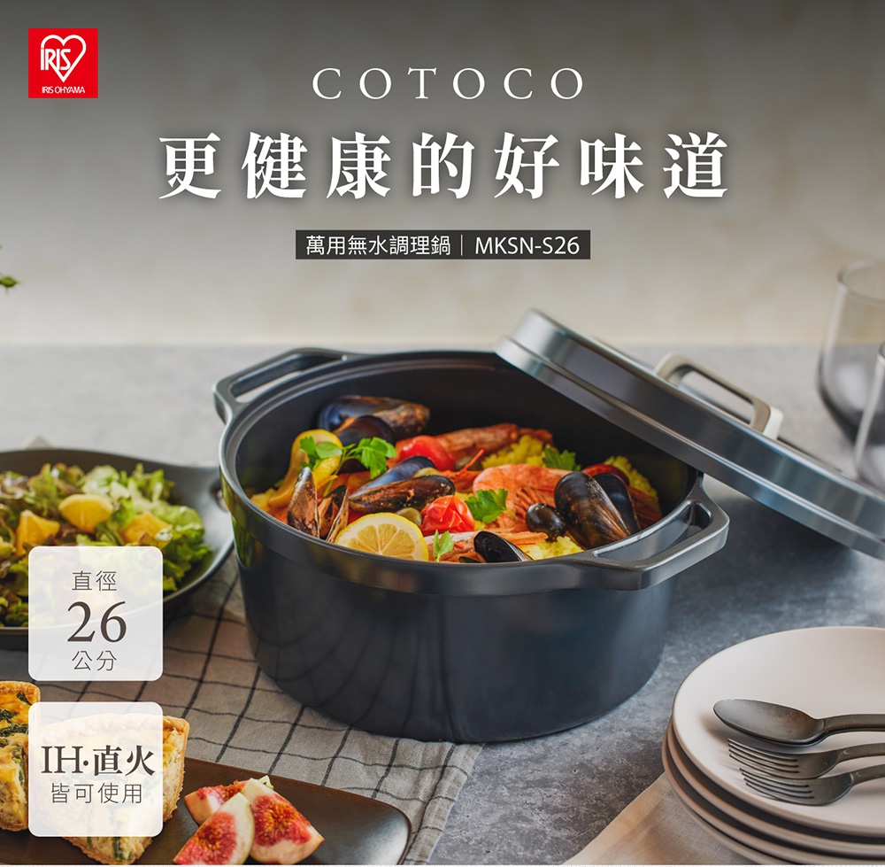 COTOCO 萬用無水調理鍋26cm MKSN-S26，為黑色鑄鐵材質，鍋蓋半開，內有海鮮燉飯，配有檸檬、番茄、淡菜和蝦。左側有沙拉，下方有烤小點和無花果。