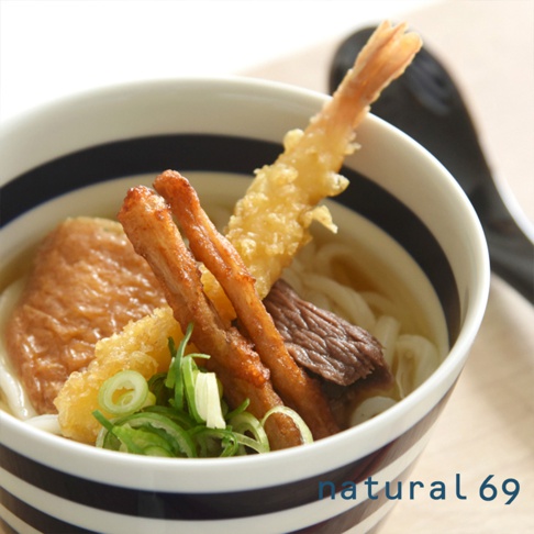 海軍風條紋丼碗內盛裝著烏龍麵，上面有炸蝦天婦羅、炸魚板、肉片、豆皮和蔥花，碗身有黑色和白色的條紋。