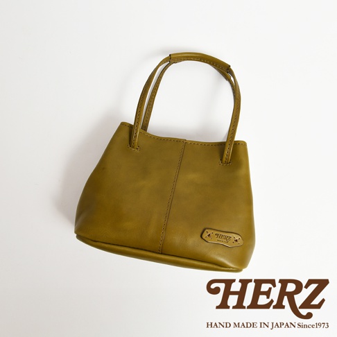 日本HERZ綠色皮革兩用托特包，包身右下方有HERZ品牌壓印，搭配手寫風格的HERZ品牌名稱。