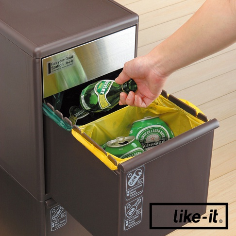 深棕色雙層分類垃圾桶，內有黃色垃圾袋，裝有綠色玻璃瓶和鋁罐。垃圾桶上有「Recycle Dust Station like-it」標誌及分類圖示。