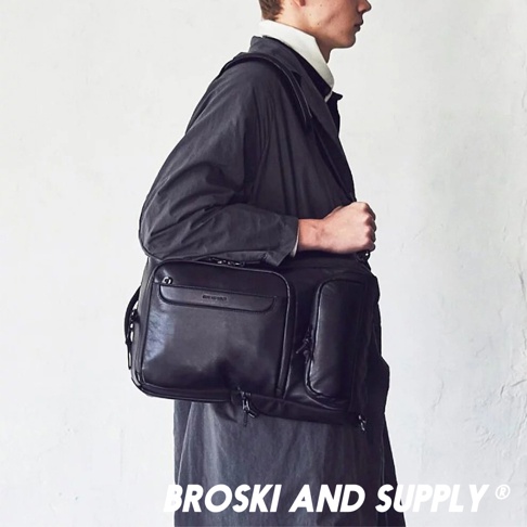一位男士身穿深色外套，展示黑色防水真皮革兩用手提後背包 LABOR mini。背包採用多隔層設計，材質光滑，質感優良。