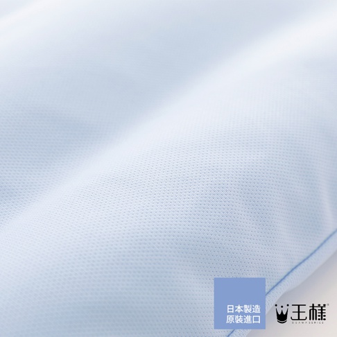 淺藍色織物枕頭特寫，紋理細膩，有波浪狀的褶皺。右下角有「日本製造 原裝進口」和「王樣」的品牌標誌。