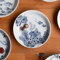 白色陶瓷小碟子，飾有藍色海洋生物圖案，包括小魚、珊瑚和海星，風格獨特，另有兩顆巧克力糖果置於碟上。