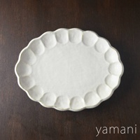 一個白色、橢圓形、帶有壓花花瓣邊緣的陶瓷料理盤，尺寸約為 30 公分。