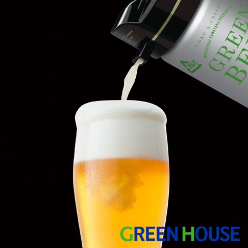 一個玻璃杯中盛有金黃色啤酒，頂部覆蓋著濃密的白色啤酒泡沫。一個黑色頂部、銀色罐身的啤酒起泡器正在傾倒，從其噴嘴流出啤酒。