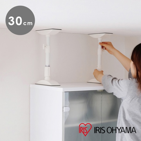 兩支白色伸縮固定棒，底部及頂部為白色方盤，中間為白色圓柱體，設有旋鈕可調整長度，固定於白色櫃頂上方，靠近天花板。