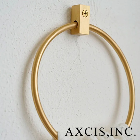 VOL 輕奢黃銅圓形毛巾環，採用黃銅材質，表面呈現溫潤的金色光澤，圓環設計簡約大方，透過螺絲固定於白色紋理牆面上，搭配一小塊白色毛巾，展現極致的輕奢質感。